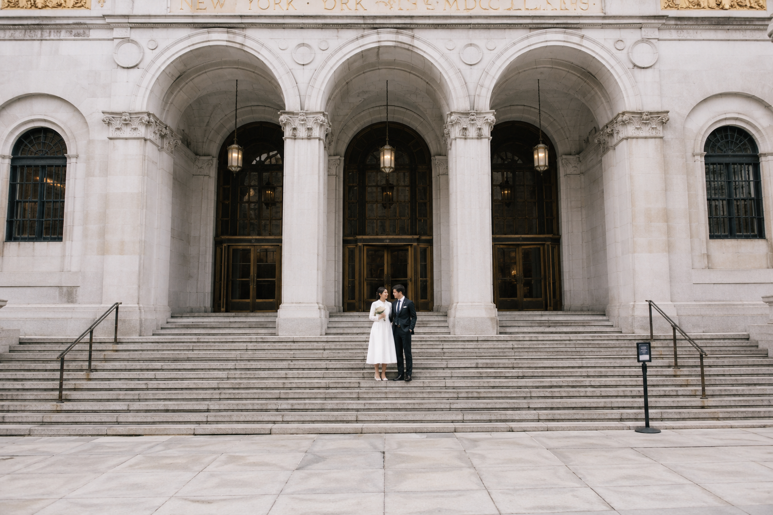 A couple on the grand stone steps of a city hall after eloping