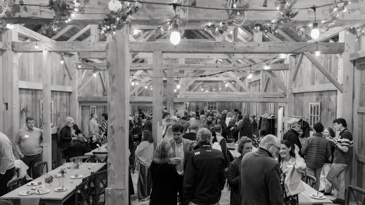 A warm, crowded barn reception strung with lights