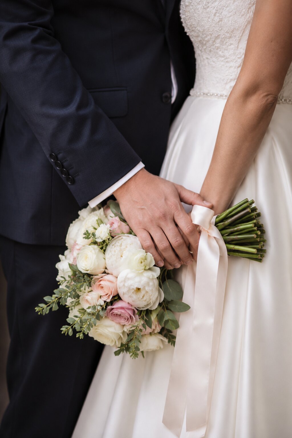 A groom holding his bride as she holds her bouquet, just married